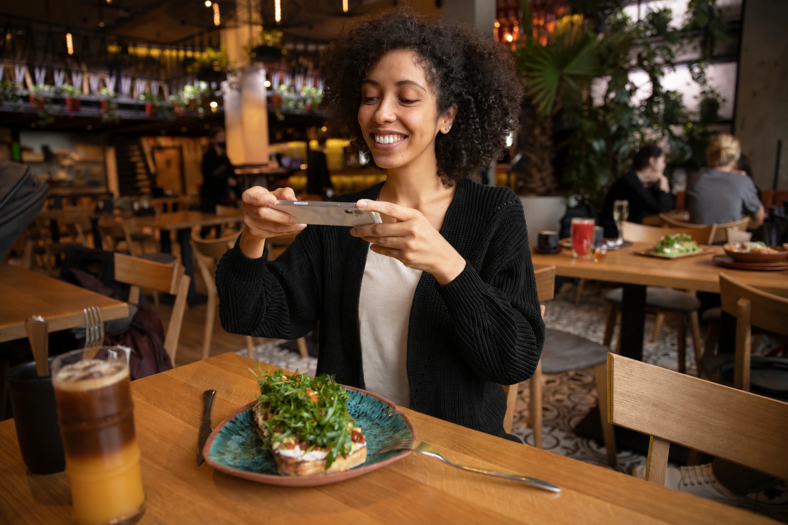 Mujer sonriente fotografiando su plato de almuerzo en un restaurante